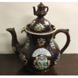 A massive pottery teapot decorated with flowers to