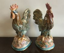 A pair of stylish pottery cockerels on floral base