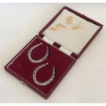 A cased pair of silver serviette rings in the form