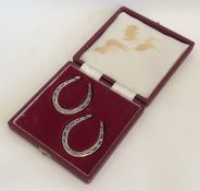 A cased pair of silver serviette rings in the form