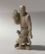 A carved ivory figure of a man in robe carrying a