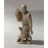 A carved ivory figure of a man in robe carrying a