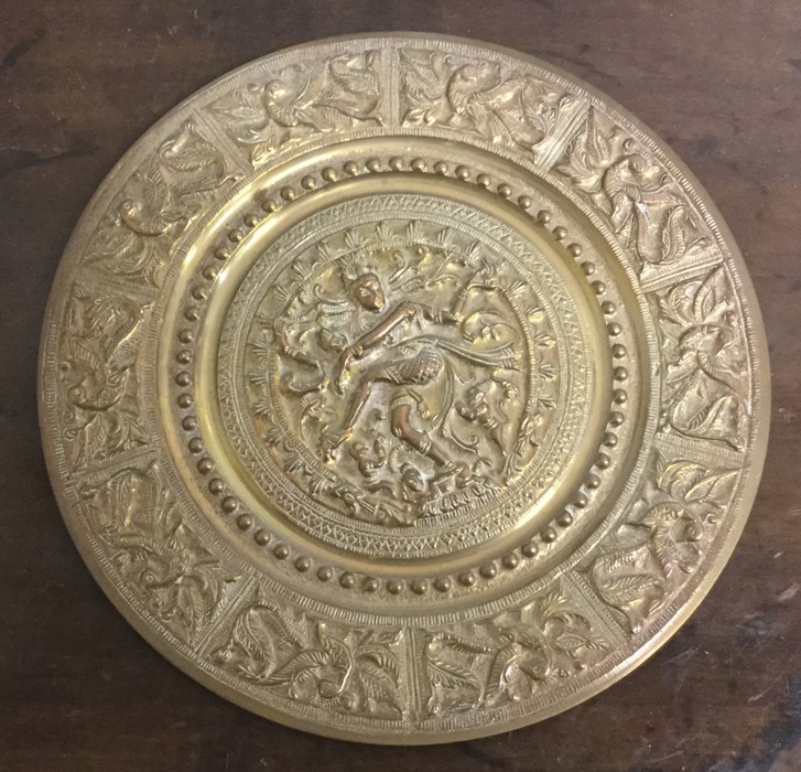 A circular Indian brass plate decorated with figur