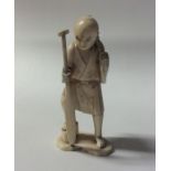 A carved ivory figure of a gentleman carrying a ba
