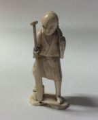 A carved ivory figure of a gentleman carrying a ba