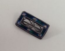 A small rectangular silver brooch with enamel deco