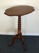 A small shaped top tripod table on three spreading