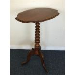 A small shaped top tripod table on three spreading