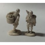 A pair of small carved ivory figures of men on ova