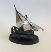 A small silver model of a junk on ebony stand. App