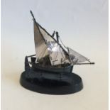 A small silver model of a junk on ebony stand. App