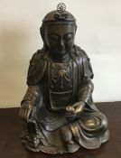 A large bronzed figure of a seated Buddha with a f