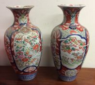 A pair of tall Imari vases decorated with bright c