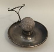 An Edwardian silver ashtray mounted with a golf ba