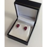 A pair of ruby and diamond oval ear studs in claw