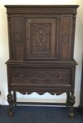 A carved oak single drawer cupboard on stretcher b