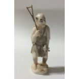 A carved ivory figure of a fisherman in standing p