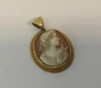 An oval gold framed cameo in relief with loop top.