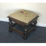 A small oak stool with tapestry seat. Est. £20 - £