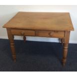 A pine two drawer writing table on turned supports