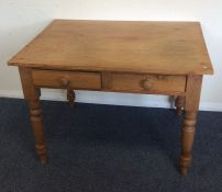 A pine two drawer writing table on turned supports