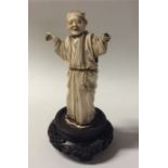 A carved ivory figure of a gentleman in robe on wo