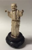 A carved ivory figure of a gentleman in robe on wo