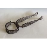 A pair of large silver and filigree sugar tongs. A