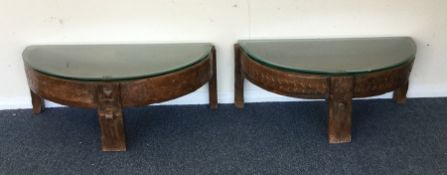 A pair of hardwood coffee tables with glass tops.