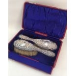 A cased pair of embossed silver brushes. Approx. 3