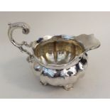 A George III silver cream jug of melon form on cas