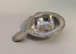 An Edwardian silver tea strainer of circular form.