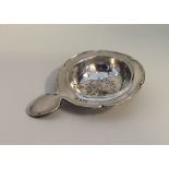 An Edwardian silver tea strainer of circular form.