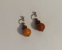 A pair of amber ear pendants with gold loop tops.