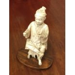 A carved ivory figure of a seated Oriental. Est. £