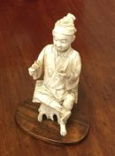 A carved ivory figure of a seated Oriental. Est. £