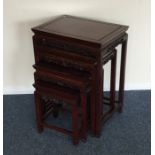 A nest of four hardwood tables of Oriental design.