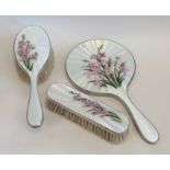 A silver and enamel three piece dressing table set