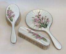 A silver and enamel three piece dressing table set