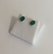 A pair of emerald ear studs in claw mounts. Approx