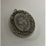 An oval silver hinged locket with ball decoration.