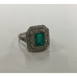 A stylish emerald and diamond cluster ring with tw