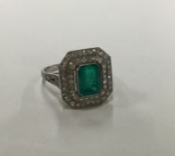 A stylish emerald and diamond cluster ring with tw