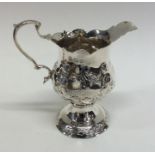 A Georgian embossed silver cream jug decorated wit