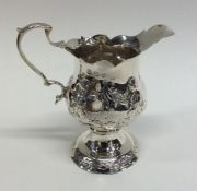 A Georgian embossed silver cream jug decorated wit