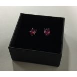 A pair of ruby ear studs in claw mounts. Est. £50