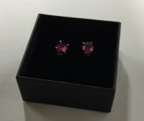 A pair of ruby ear studs in claw mounts. Est. £50