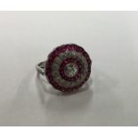 A circular ruby and diamond three row cluster ring