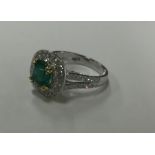 A large emerald and diamond cluster ring in two co
