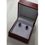 A pair of amethyst ear studs contained within a bo